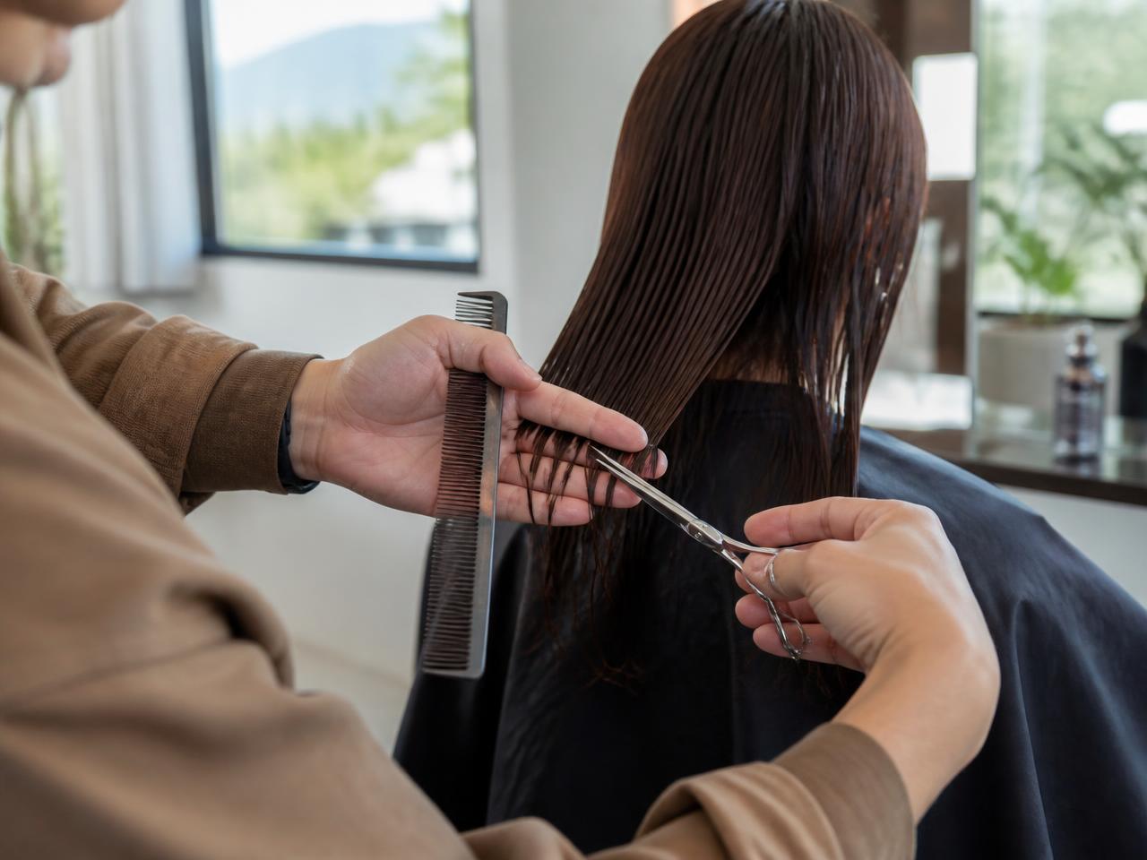 Hairstylist cutting a client's hair with scissors and a comb