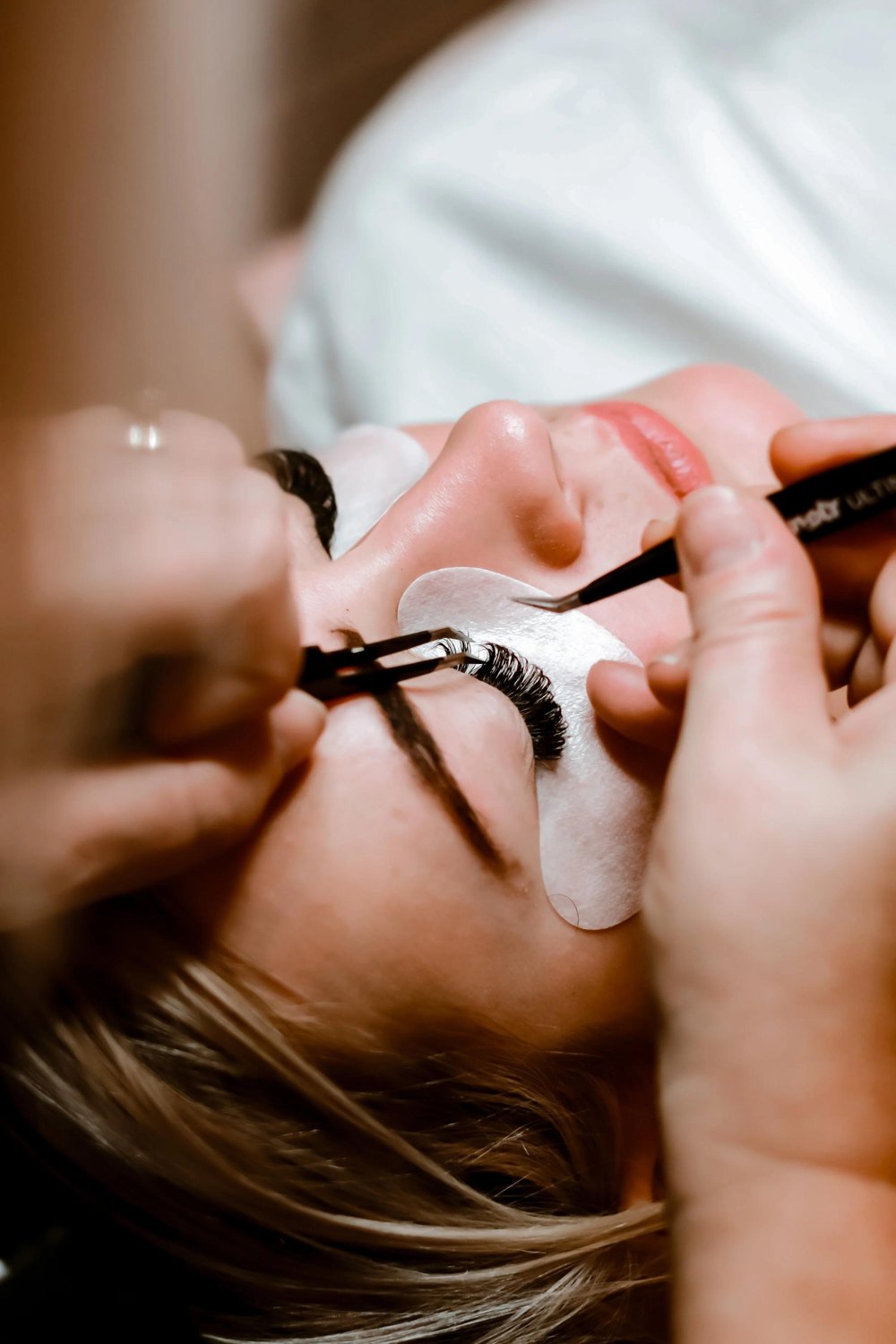 Lash technician applying extensions to a client's eyelashes